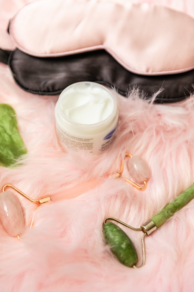 Jade Rollers and Facial Cream Beside an Eye Mask
